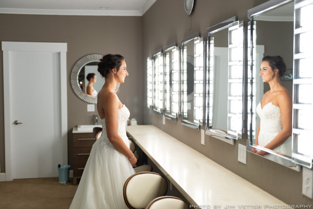 Bride standing at the lighted makeup mirrors inside the Deer Park Villa Bridal Cottage
